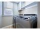 Bright laundry room with large stainless steel washer and dryer with a window and overhead storage at 10510 Berthoud Way, Parker, CO 80134