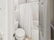 Bright bathroom with a toilet, tub with white shower curtain, and a gray door at 12912 Grant Cir # A, Thornton, CO 80241