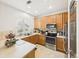 Bright kitchen featuring stainless steel appliances, wood cabinetry, and a window overlooking the neighborhood at 12912 Grant Cir # A, Thornton, CO 80241