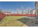 A large backyard features a lush lawn, a patio area, a red fence, and mature trees providing shade and privacy at 20229 E Red Fox Ln, Centennial, CO 80015