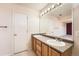 Well-lit bathroom with dual sinks, wood cabinetry, large mirror and convenient doorway at 20229 E Red Fox Ln, Centennial, CO 80015