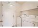 A functional laundry room with a washer, dryer, storage shelves, and a convenient coat rack by the door at 20229 E Red Fox Ln, Centennial, CO 80015