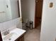 Traditional bathroom featuring a white sink, toilet, and tile, with gold accents and a view into an additional room at 14963 E Adriatic Pl, Aurora, CO 80014