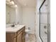 Bathroom with single sink vanity, neutral tile, and shower with glass door at 6768 Vivian St, Arvada, CO 80004