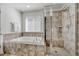 Luxurious bathroom featuring a soaking tub, separate shower with glass door, and neutral tile at 7686 Grady Cir, Castle Rock, CO 80108