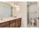 Modern bathroom with a wood vanity, white counter, and a glass-enclosed shower at 20578 E 63Rd Ave, Aurora, CO 80019