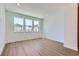 Bright bedroom with three large windows providing natural light and light, wood-look flooring at 20578 E 63Rd Ave, Aurora, CO 80019