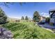 Manicured backyard featuring a spacious lawn, mature trees, and a charming split rail fence at 7067 Gray Fox Ct, Highlands Ranch, CO 80130