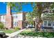 Attractive townhome with a brick facade, front porch seating, mature trees, and manicured lawn at 9713 W Chatfield Ave # F, Littleton, CO 80128