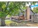 Charming exterior view of the home with a spacious deck, brick chimney, and well-kept lawn surrounded by mature trees at 13610 W Dakota Pl, Lakewood, CO 80228