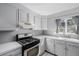 Well-lit kitchen featuring white cabinets, stainless steel oven, modern countertops and tile backsplash at 13610 W Dakota Pl, Lakewood, CO 80228