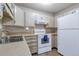Well-lit kitchen with white cabinets, a double sink, and matching white appliances at 13606 E Bates Ave # 102, Aurora, CO 80014