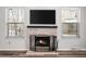 Cozy living room featuring brick fireplace with TV, large windows with blinds, and hardwood flooring at 1712 S Kline Way, Lakewood, CO 80232