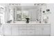 Bright bathroom featuring a double vanity with white cabinets, and a large mirror with elegant lighting at 6128 Songbird Cir, Boulder, CO 80303