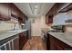 Galley kitchen featuring stainless steel appliances, granite countertops, dark wood cabinets and wood-look floors at 13393 E Asbury Dr # 103, Aurora, CO 80014