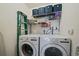 Bright laundry room with modern washer and dryer units and storage shelves at 13393 E Asbury Dr # 103, Aurora, CO 80014