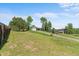 Expansive grassy front yard with mature trees leading to a cozy home with a driveway at 8427 S Custer Ln, Evergreen, CO 80439