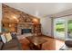Cozy living room with brick fireplace, wood floors, and sliding doors to the backyard at 8427 S Custer Ln, Evergreen, CO 80439