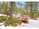 Nestled in trees, a deck with seating provides an outdoor getaway at 5575 Jackpine Rd, Evergreen, CO 80439