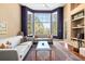 Bright living room with floor-to-ceiling windows, fireplace, hardwood floors, neutral furniture, and stylish decor at 5575 Jackpine Rd, Evergreen, CO 80439