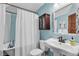 Cozy blue bathroom with pedestal sink, dark wood medicine cabinet and bathtub with shower at 310 Judson St, Longmont, CO 80501