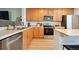 Well-lit kitchen featuring stainless-steel appliances, wood cabinets, and light wood flooring at 371 Smith Cir, Erie, CO 80516