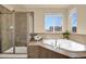 Bathroom showcasing a tiled shower with glass door and a soaking tub with tiled surround and a window at 24269 E Arapahoe Pl, Aurora, CO 80016