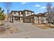 A tan two-story home with a three-car garage, brick accents, and a concrete driveway under a blue sky at 24269 E Arapahoe Pl, Aurora, CO 80016