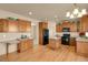 Bright kitchen with wood cabinets, black appliances, an island, and an adjacent seating area at 24269 E Arapahoe Pl, Aurora, CO 80016