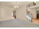 An open-concept living room featuring neutral-colored walls, carpet flooring, and access to a staircase and dining area at 24269 E Arapahoe Pl, Aurora, CO 80016