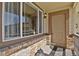 A home's front porch featuring brick accents, a large window, and a tan front door with a black mat at 24269 E Arapahoe Pl, Aurora, CO 80016