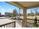 Home's covered front porch with brick columns and wood railing, offering a view of the landscaped neighborhood at 24269 E Arapahoe Pl, Aurora, CO 80016