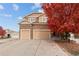 Charming two-story home with attached three-car garage and welcoming curb appeal with fall foliage at 15003 W 63Rd Ave, Arvada, CO 80403