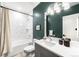 Stylish bathroom features a shower-tub combo with white tile and vanity with a dark green wall at 556 Monroe St, Denver, CO 80206