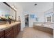 Bathroom featuring a double vanity, soaking tub, and access to a walk-in closet at 11935 E Lake Ct, Greenwood Village, CO 80111