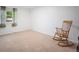 Bright, carpeted bedroom featuring a classic rocking chair and natural light from a window at 7659 S Holland Way, Littleton, CO 80128