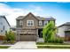 Two-story home with stone accents, a two-car garage, solar panels, and a well-maintained front yard at 985 S Elk Way, Aurora, CO 80018