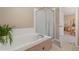 Bathroom featuring a soaking tub with tile surround and glass-enclosed shower, creating a spa-like experience at 9230 W Indore Dr, Littleton, CO 80128