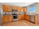 Functional kitchen with wood cabinets and stainless steel appliances at 9230 W Indore Dr, Littleton, CO 80128