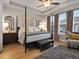 Comfortable primary bedroom features a four-poster bed, wood floors, and sunny windows at 9035 S Shawnee Ct, Aurora, CO 80016