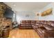 Cozy living room featuring a stone fireplace, hardwood floors, and a comfortable brown leather sectional sofa at 20155 E Davies Ave, Centennial, CO 80016