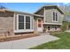 Up close front view of house with brick and siding with a well manicured lawn at 8001 S Estes St, Littleton, CO 80128