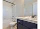 Bathroom featuring a shower-tub combination, white tile surround and a blue vanity at 3411 N Xenia St, Denver, CO 80238