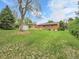 Spacious backyard with mature trees, grassy lawn, brick home and outbuildings at 2797 S Newton Way, Denver, CO 80236