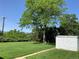 Spacious backyard with a beautiful mature tree, storage shed, and green grass lawn at 2797 S Newton Way, Denver, CO 80236