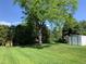 Expansive backyard featuring a large shade tree and storage shed on a lush green lawn at 2797 S Newton Way, Denver, CO 80236