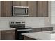Close up of stainless steel microwave and oven with dark wood cabinets and white subway tile backsplash at 20871 E 60Th Ave, Aurora, CO 80019