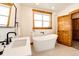 Stylish bathroom with a soaking tub, modern fixtures, and a rustic wood door for added charm at 6191 S Olathe St, Centennial, CO 80016