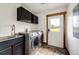 Laundry room with stainless steel washer and dryer, storage cabinets, tile flooring, and door to the outside at 6191 S Olathe St, Centennial, CO 80016