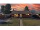 Brick home with manicured front yard and convenient carport under a colorful sunset at 7081 Warren Dr, Denver, CO 80221